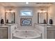 Elegant bathroom featuring a soaking tub, dual vanities, decorative mirrors, and modern lighting at 364 Pecan Valley Way, Four Oaks, NC 27524