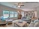 Bright living room with a ceiling fan, large windows, and an open floor plan leading to the kitchen at 46 Shortstop Cir, Four Oaks, NC 27524