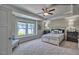 Spacious main bedroom featuring a tray ceiling, ceiling fan, large window, and neutral carpeting at 46 Shortstop Cir, Four Oaks, NC 27524