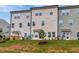 Townhome featuring light beige siding, many windows, a grassy backyard and trees at 7117 Hubner Pl # 22, Cary, NC 27519
