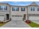 Charming townhome featuring a two-car garage, black shutters, and light beige siding at 7117 Hubner Pl # 22, Cary, NC 27519
