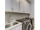 Laundry room with white cabinets, a stainless steel sink, and modern washer/dryer at 1016 Dozier Way, Cary, NC 27518