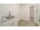 A functional laundry room with granite countertops, white cabinets, utility sink, and closet access at 250 Ellington Rd, Graham, NC 27253