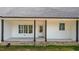 A charming porch with white siding, a dark roof, and a well-manicured lawn surrounded by lush greenery at 250 Ellington Rd, Graham, NC 27253