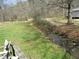 Grassy backyard with a small creek running through the property at 306 Eastway Ln, Graham, NC 27253