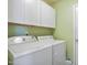 Laundry room with side-by-side washer and dryer and white cabinets for storage at 701 Brickstone Dr, Apex, NC 27502