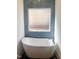 Freestanding soaking tub in tiled bathroom with blue accent tiles and frosted window at 727 Cook Rd, Durham, NC 27713