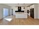 Open kitchen featuring white cabinetry, stainless steel appliances, tile backsplash, an island, and hardwood floors at 727 Cook Rd, Durham, NC 27713