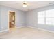 Bedroom showcasing ceiling fan, window, neutral carpet, and ensuite bathroom at 125 Watertree Ln, Apex, NC 27502