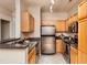 Galley kitchen featuring stainless steel appliances, granite countertops and natural-toned wood cabinets at 1300 Durlain Dr # 108, Raleigh, NC 27614