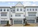Three-story townhome featuring gray and white siding, black trim and a two car garage at 4804 Cypress Tree Ln, Raleigh, NC 27612