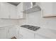 Close up of the gas range and ventilation hood in a modern white kitchen at 4804 Cypress Tree Ln, Raleigh, NC 27612