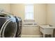 Clean laundry room featuring modern washer and dryer, sink and storage shelf at 12408 Angel Vale Pl, Durham, NC 27703