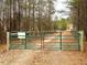 Green metal gate opens to a long wooded driveway at 330 Ellis Stewart Ln Ln, Cameron, NC 28326