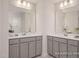 Well-lit bathroom featuring double vanity with gray cabinets, white countertops, and stylish mirrors at 3854 Well Fleet Drive, Fuquay Varina, NC 27526