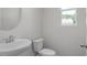 Modern half bathroom with a pedestal sink, toilet, and a round mirror at 3854 Well Fleet Drive, Fuquay Varina, NC 27526
