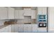 Bright kitchen with white cabinets, stainless steel appliances, and a stylish vent hood, ready for cooking at 3854 Well Fleet Drive, Fuquay Varina, NC 27526