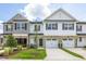 New townhome showcasing a stone facade, white siding, black shutters, and a two-car garage at 3860 Well Fleet Drive, Fuquay Varina, NC 27526
