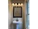 Bathroom featuring pedestal sink with a dark framed mirror, lighting and window at 412 N Cooper St, Clayton, NC 27520