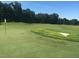 A serene golf course featuring a manicured green and sand trap, set against a backdrop of tall trees at 7845 Hasentree Lake Dr, Wake Forest, NC 27587