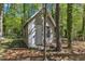 Exterior view of charming outbuilding with white door in a wooded backyard at 1304 Rothes Rd, Cary, NC 27511