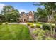 Stately brick home with lush landscaping, circular driveway, and mature trees under a blue sky at 2035 Stuart Ct, Burlington, NC 27215