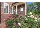 Charming brick home exterior with colorful roses, manicured landscaping, and covered front porch at 2035 Stuart Ct, Burlington, NC 27215
