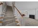 Carpeted staircase with wood railing leading to a cozy living area with a fireplace at 2035 Stuart Ct, Burlington, NC 27215