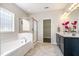 Bright bathroom with a large tub, glass shower, and dark vanity with double sinks at 218 Strolling Way, Durham, NC 27707