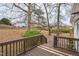 View of backyard from a wooden deck with mature trees and leaf-covered lawn at 2400 Dorety Pl, Raleigh, NC 27604
