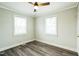 Bright bedroom featuring a modern ceiling fan, wood-look flooring, and two windows at 2400 Dorety Pl, Raleigh, NC 27604