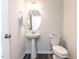 Small bathroom features a pedestal sink, oval mirror, and a classic white toilet at 5238 Beardall St, Raleigh, NC 27616