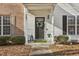 Inviting front entry featuring a black door with a wreath, enhanced by a covered porch and neat landscaping at 5809 Neuse Wood Dr, Raleigh, NC 27616