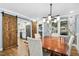 Elegant dining room with wooden table and chairs, modern lighting, and barn door to kitchen at 5920 Whittier Dr, Raleigh, NC 27609