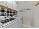 Bright laundry room featuring a modern washer and dryer, stylish cabinets and a trendy black and white backsplash at 75 Pearsall Farm Ln, Clayton, NC 27527