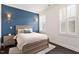 Inviting bedroom with a blue accent wall, sconce lighting, and bright windows with white shutters at 1141 Barley Stone Way, Raleigh, NC 27603