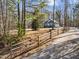 A view of a blue house with white trim, with surrounding trees, seen through a wooden fence at 125 Sue-Kim Dr, Youngsville, NC 27596