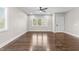 Bright room with hardwood floors, featuring windows looking out to trees, and a modern ceiling fan at 125 Sue-Kim Dr, Youngsville, NC 27596