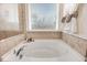 Corner soaking tub with window in the main bathroom, accented with neutral tile at 130 Daniel Farm Dr, Benson, NC 27504