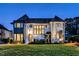 Elegant white brick home with beautiful landscaping illuminated at twilight showcases classic architectural design at 1324 Brooks Ave, Raleigh, NC 27607