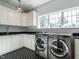 Well-lit laundry room features modern stainless steel washer and dryer with sleek black and white herringbone flooring at 1324 Brooks Ave, Raleigh, NC 27607