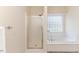 Bright bathroom featuring a glass door shower and a tub with a tiled base beneath a patterned glass window at 1000 W Landing Dr, Sanford, NC 27330
