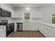 Bright kitchen features stainless appliances, white cabinets and countertops, and wood-look floors at 5110 Chipstone Dr, Raleigh, NC 27610