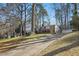 Exterior view of the home features mature trees and a long driveway to the main house at 5410 Thayer Dr, Raleigh, NC 27612