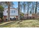View of home's exterior with mature trees on a sunny day; home features white and brick at 5410 Thayer Dr, Raleigh, NC 27612