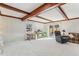 Bright living room featuring exposed beams, a large window, sliding glass doors and neutral-colored carpet at 5410 Thayer Dr, Raleigh, NC 27612