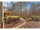 Backyard with wooden deck, mature trees, and stone pathway through the landscaping at 10014 Hammock Bend Bnd, Chapel Hill, NC 27517