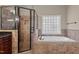 Bathroom features a glass shower, soaking tub, tile flooring, and a large grid pattern window at 10014 Hammock Bend Bnd, Chapel Hill, NC 27517