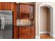 Cherry dry bar with a wine rack, glass front cabinets, and granite countertops, accented by an arched doorway at 10014 Hammock Bend Bnd, Chapel Hill, NC 27517