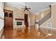 Open living room with hardwood floors, stone fireplace, built-in cabinets, and a staircase to the upper level at 10014 Hammock Bend Bnd, Chapel Hill, NC 27517